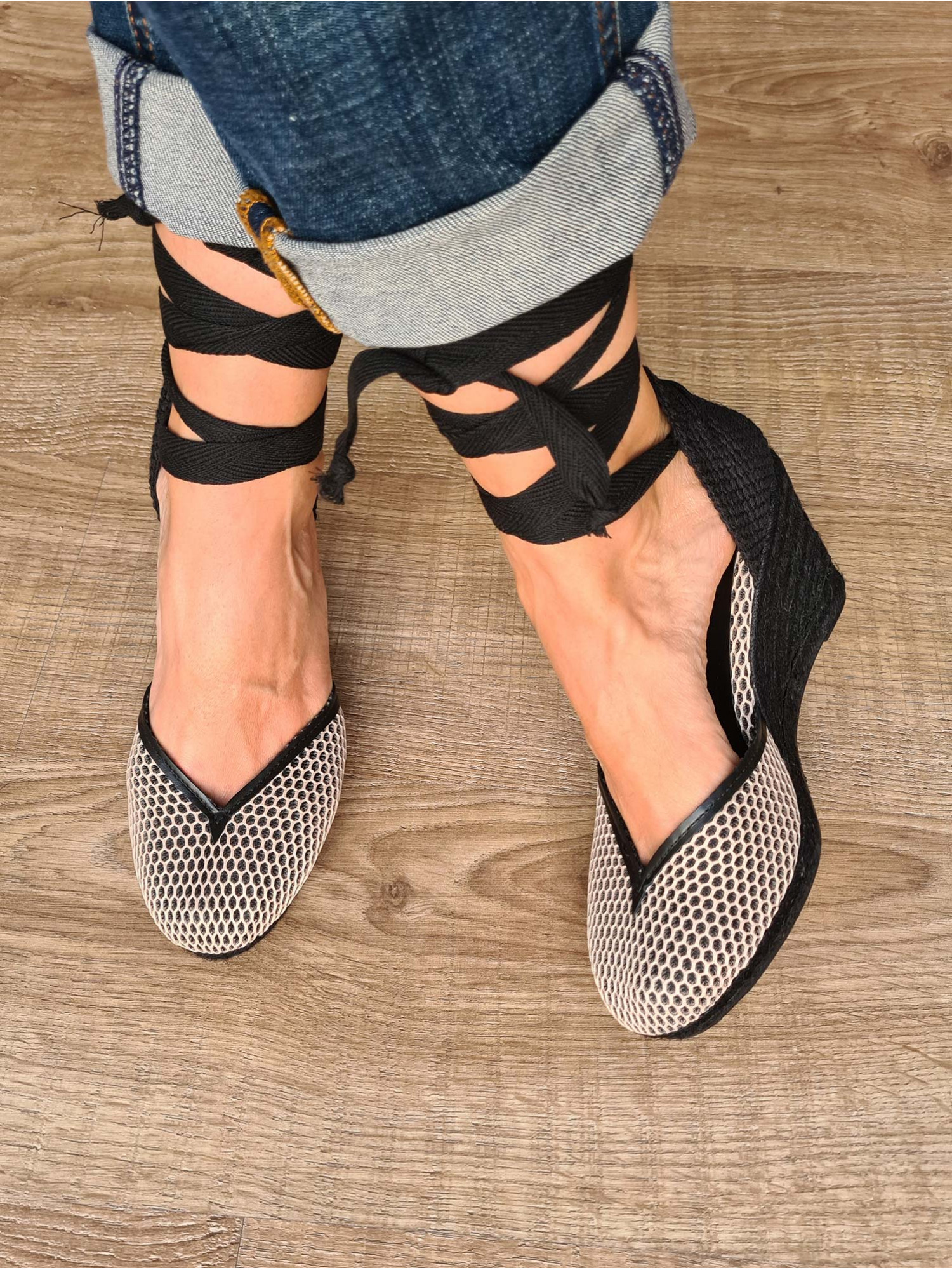 Sandalias de piel con cuña de esparto, cierre en cintas atadas a la pierna y tela en rejilla. Producto artesano 100% español.